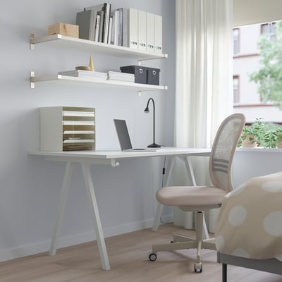 Minimalista otthoni iroda TROTTEN íróasztallal, laptoppal, lámpával, polcokkal és pöttyös székkel; természetes fényű ablak.