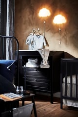 Óvoda fekete bútorokkal, felhőlámpákkal, szürke falakkal, kék takaróval, törölközőkkel.