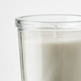 Clear glass candle holder half-filled with creamy white wax, high-quality, handmade look.