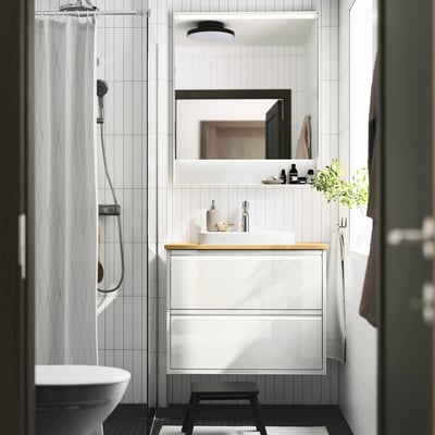 Modern bathroom with ÄNGSJÖN furniture, black accents, glass shower, plants, and bamboo vanity.
