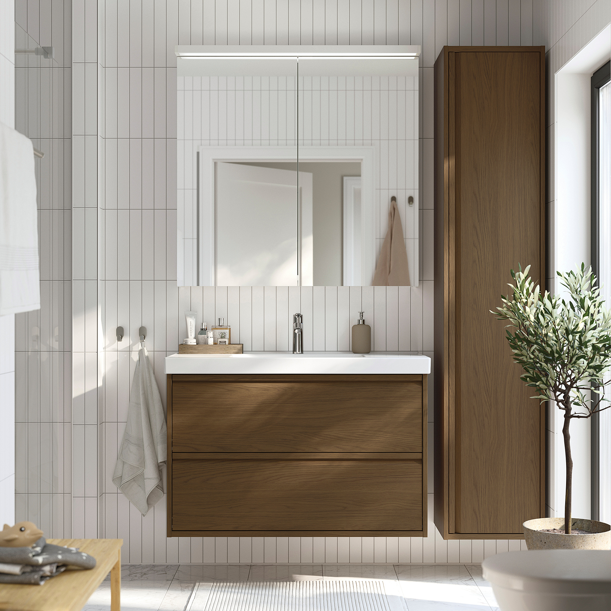Modern bathroom with brown oak cabinet, sink, mirror, and plant.