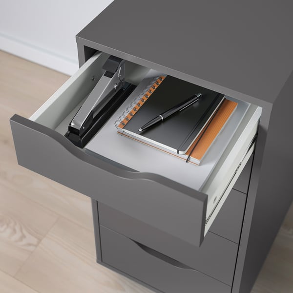 Open desk drawer revealing notebook, pen, and stapler. Part of ALEX series, designed for organized storage with drawer stops.