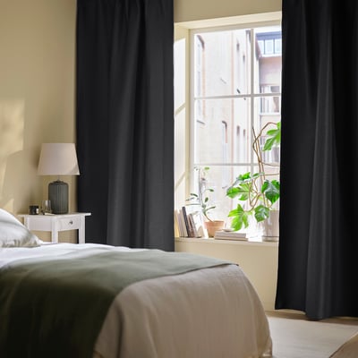Minimalist bedroom with large ANNAKAJSA anthracite curtains, tall and narrow window, small table lamp, cozy bed.
