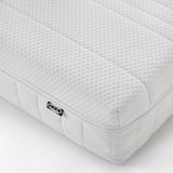 Close-up of IKEA ÅNNELAND mattress, showcasing its firm, textured white surface with a small brand label, emphasizing quality and comfort.
