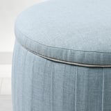 Close-up of a modern, light blue pouffe showcasing its quality stitching and upholstery details.