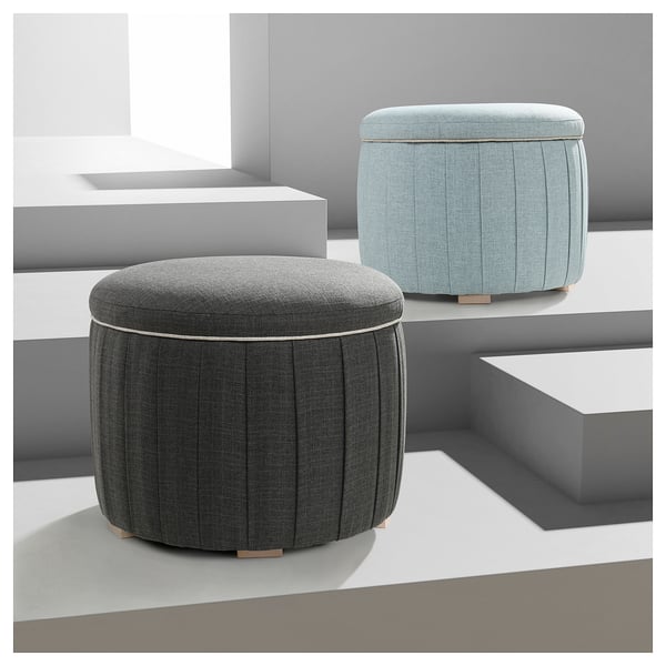 Two cylindrical footstools displayed, one grey, one light blue, with pleated sides and wooden legs.