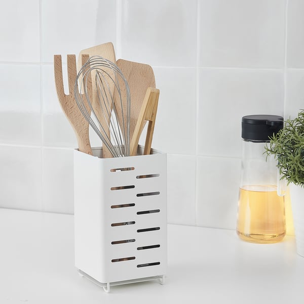 Wooden utensils in white drying rack with holes for air circulation on counter.