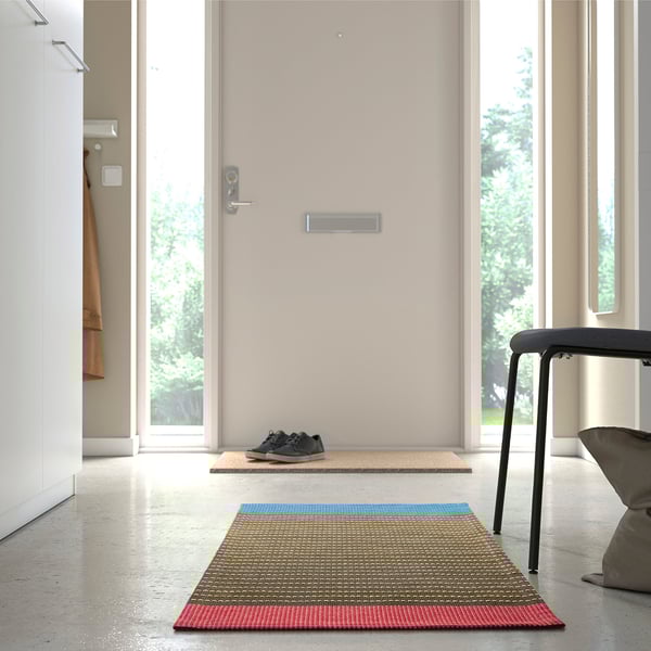 Bright rug with yellow, blue, and red stripes welcomes you at the door, adding color to the entryway.