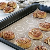 Baking tray with cinnamon rolls, some on plate, sprinkled with sugar.