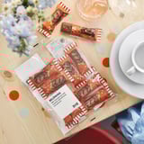 Open chocolate bars on table near flowers, glasses, and plates. Ready to eat.