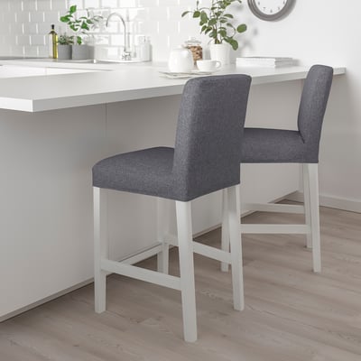 Two grey bar stools with white frames under kitchen counter, small plant, cozy vibe, cushioned, stable legs.