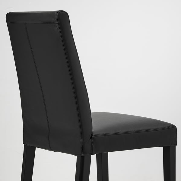 Black leather dining chair; sleek design, padded seating, sturdy wooden legs.