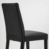 Black leather dining chair; sleek design, padded seating, sturdy wooden legs.