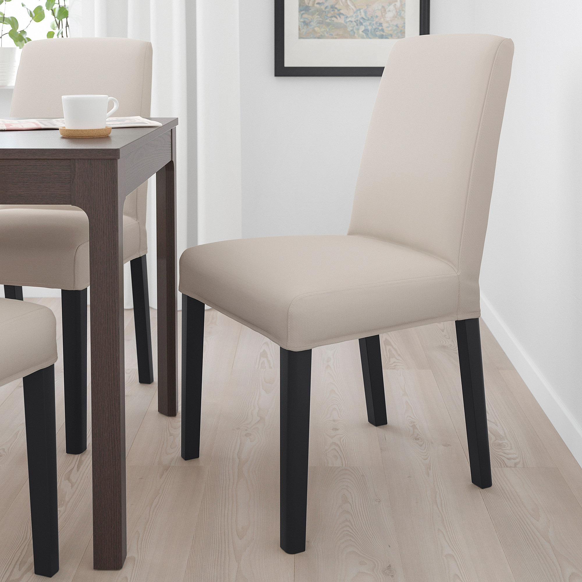 Beige BERGMUND chairs with black legs around small table, padded for comfort.