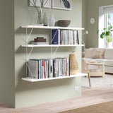 White wall shelf with items against sage green wall in beige living room.