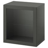 A dark green, cubed storage unit with a glass door. It has a shelving design and is part of the BESTÅ collection.