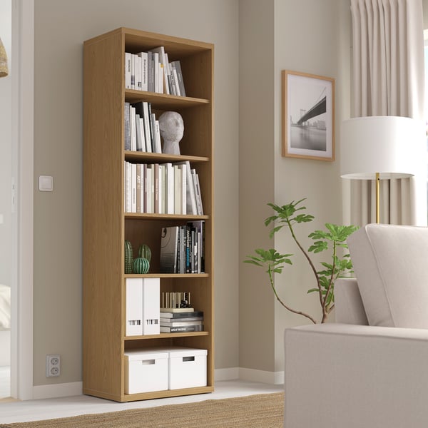 Tall BESTÅ bookshelf with books & decor, between sofa & window.