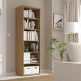 Tall BESTÅ bookshelf with books & decor, between sofa & window.