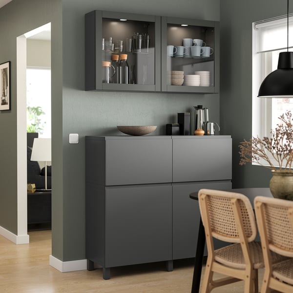 Modern grey kitchen corner with glass & solid doors, wicker chairs, pendant lamp, green walls.