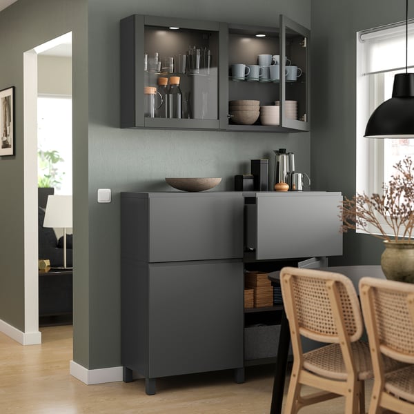 Modern living room featuring dark grey BESTÅ storage units with glass doors and wooden chairs.