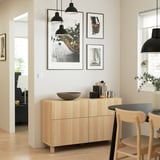 Modern living room with BESTÅ sideboard, artwork, lights, and dining area.
