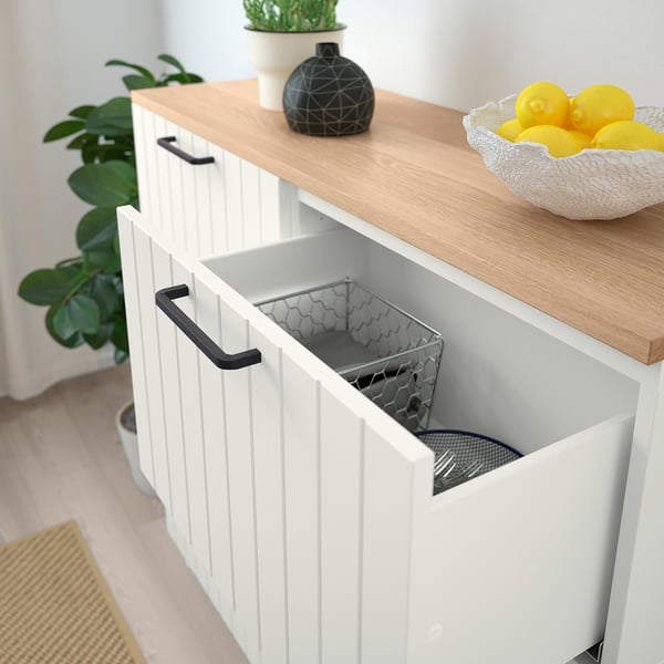 White BESTÅ cabinet with one open drawer revealing a metal mesh basket, set against a bright, modern aesthetic.