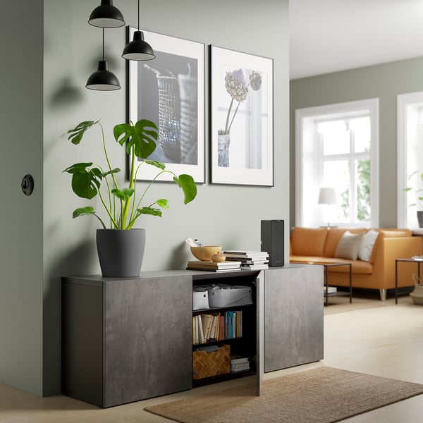 Modern living room with grey storage, plant, books, art, orange sofa, and lamps.