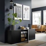 Modern living room with dark walls, plant, orange couch, pendant lamps, & art prints.
