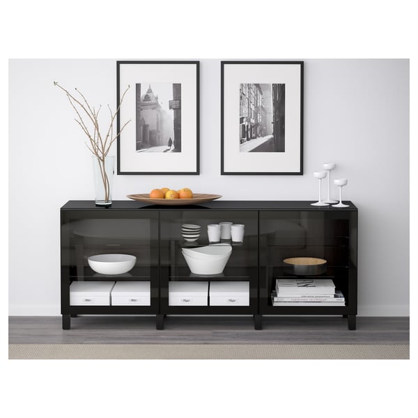 Black glass storage cabinet with tempered glass doors. Top has fruit dish, cups, and vase with branches. Wall-mounted, protects belongings from dust.