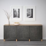 Gray sideboard with wooden top, two black & white framed photos, bowl of oranges, and vase.