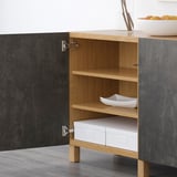 A modern wooden cabinet with open door showing shelves, white boxes, and a bowl.