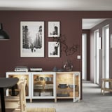 Modern living room with BESTÅ sideboard, displaying dishes, decor, and photos. Lit shelves and wall art.