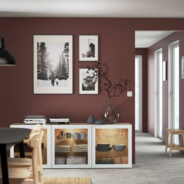 Minimalist dining room with maroon walls, white sideboard, pendant light, & three photos. Cozy table setup.