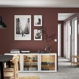 Minimalist dining room with maroon walls, white sideboard, pendant light, & three photos. Cozy table setup.