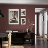 Modern dining room with burgundy walls, dark furniture, glass doors, and decor.