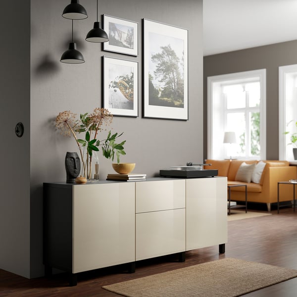 BESTÅ sideboard with black legs, decorated with vase, bowl, record player. Orange sofa, lamp, and rug in background.