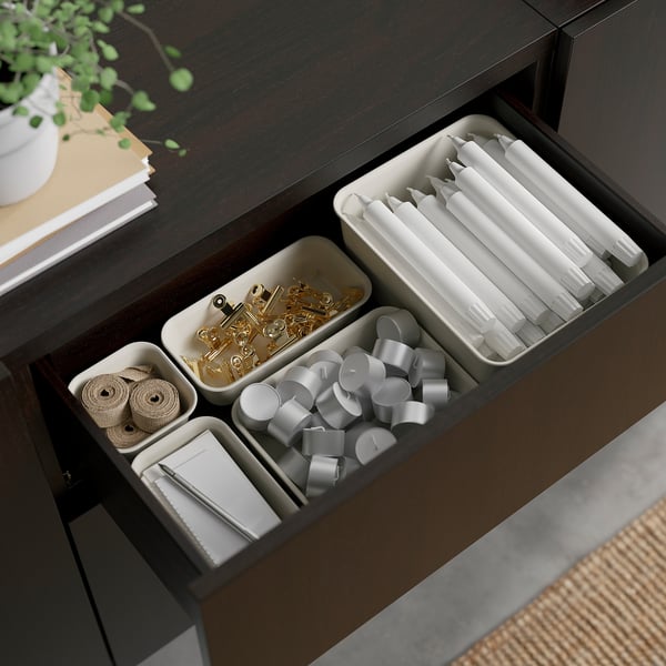 Open drawer with organized office supplies: clips, ties, pens, and ribbons in compartments.