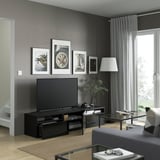 Modern living room with BESTÅ tv bench, flat-screen tv, and framed pictures. Includes shelves for storage and cable management.