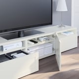 Modern white tv stand with open drawers showing gaming controllers and console, neatly organized with cable management and adjustable shelves.