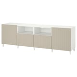 White BESTÅ tv unit with beige panels, vertical grooves, adjustable shelves, and four legs.