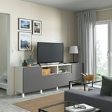 Grey BESTÅ tv bench with shelves & drawers, flat-screen tv, lamp, cabinet, coffee table & sofa in modern living room.