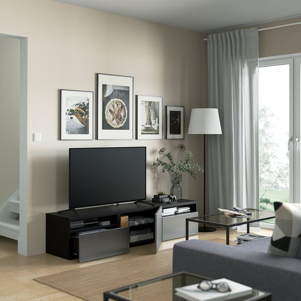 Modern living room with BESTÅ tv bench, adjustable feet, cable management, and drawers. Central tv, wall art, lamp, glass coffee table, and sofa.