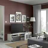 Modern living room with maroon wall, tv stand, flat-screen tv, framed art, and glass coffee table.