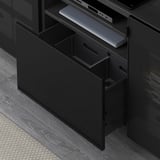 Black wooden tv stand with drawer partially open. Holds electronics and has cable management.