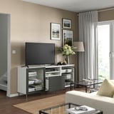 Modern living room with BESTÅ tv unit featuring a flat screen tv, decorative flowers, and framed artwork on beige walls.