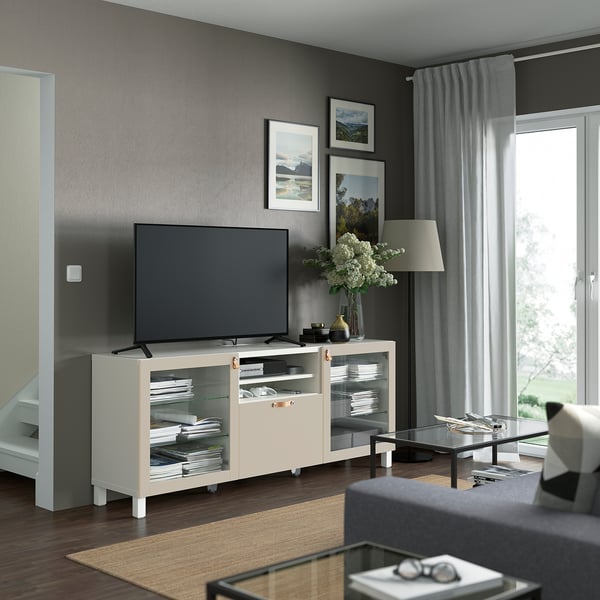 Modern living room with BESTÅ tv bench in white, glass doors, central tv, gray curtains, photos, black coffee table, gray sofa.