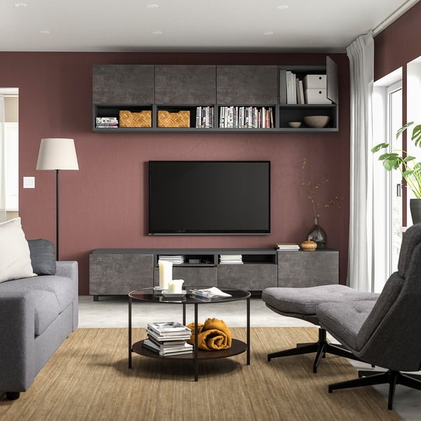 Modern living room with maroon walls, grey furniture, wooden coffee table, and flat-screen tv.