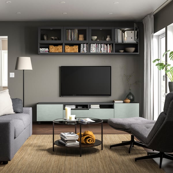 Modern living room with gray walls, gray sofa, black tv, glass coffee table, and BESTÅ tv bench in turquoise and black.