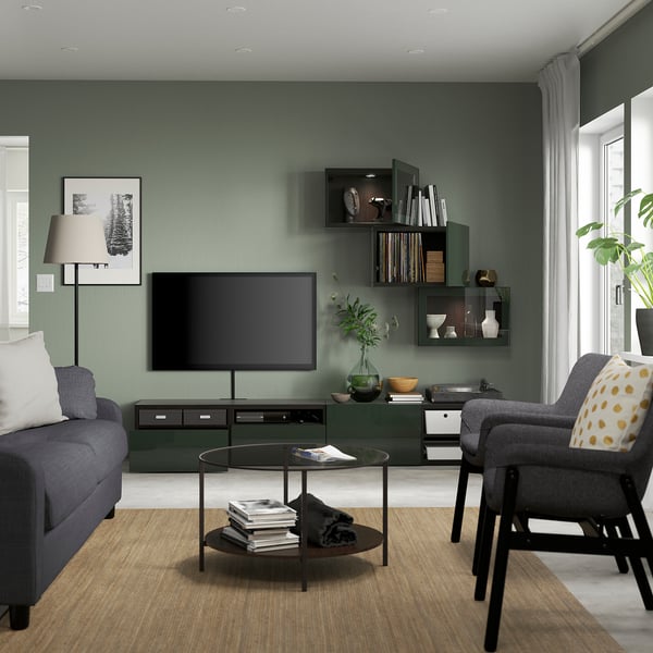 Modern green living room with gray sofa, tv on storage unit, large windows.