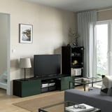 Modern living room with BESTÅ tv unit, flat-screen tv, storage shelves, table lamp, and glass coffee table with magazines.